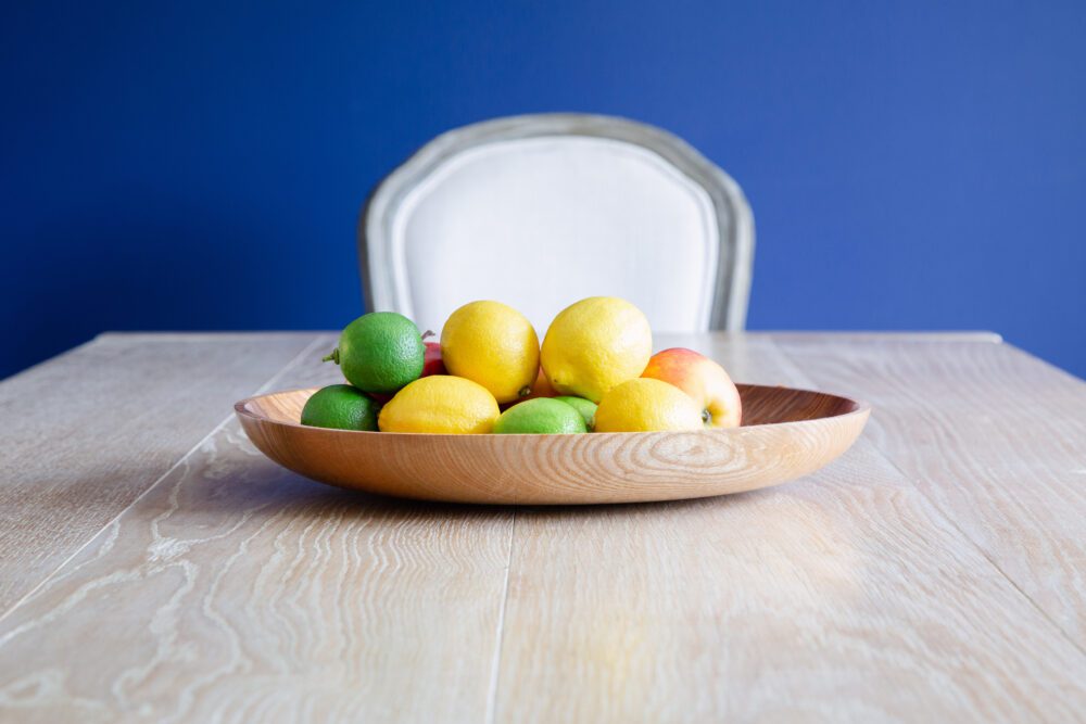 Blue wall with pale dining table and fruit bowl