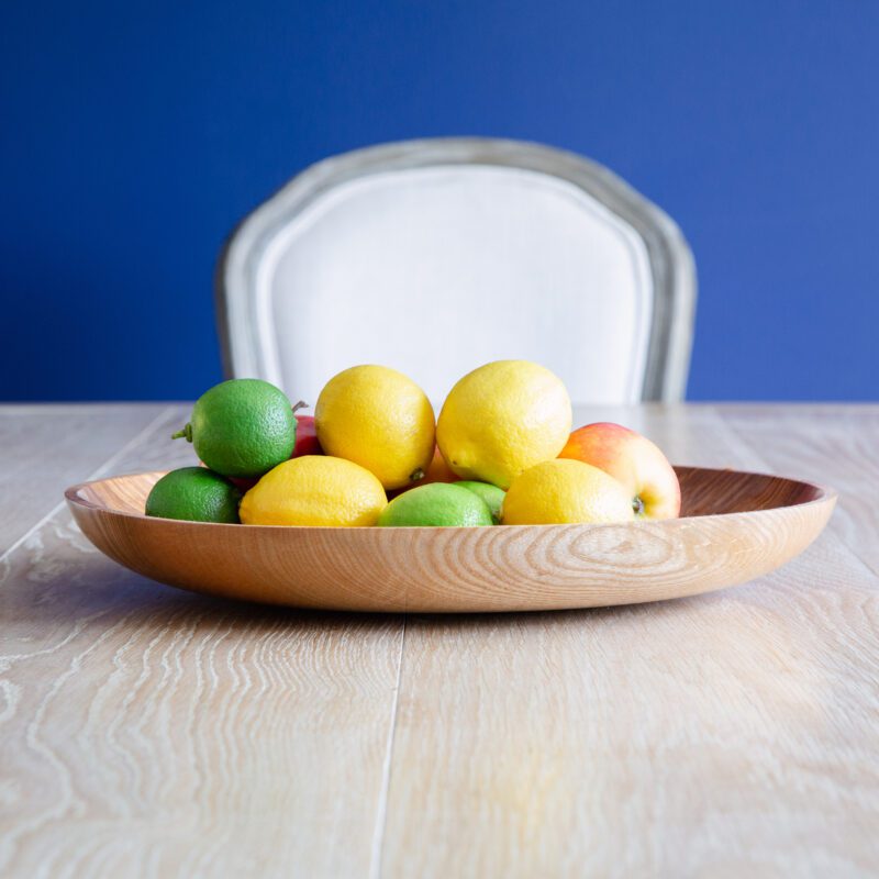 Blue wall with pale dining table and fruit bowl